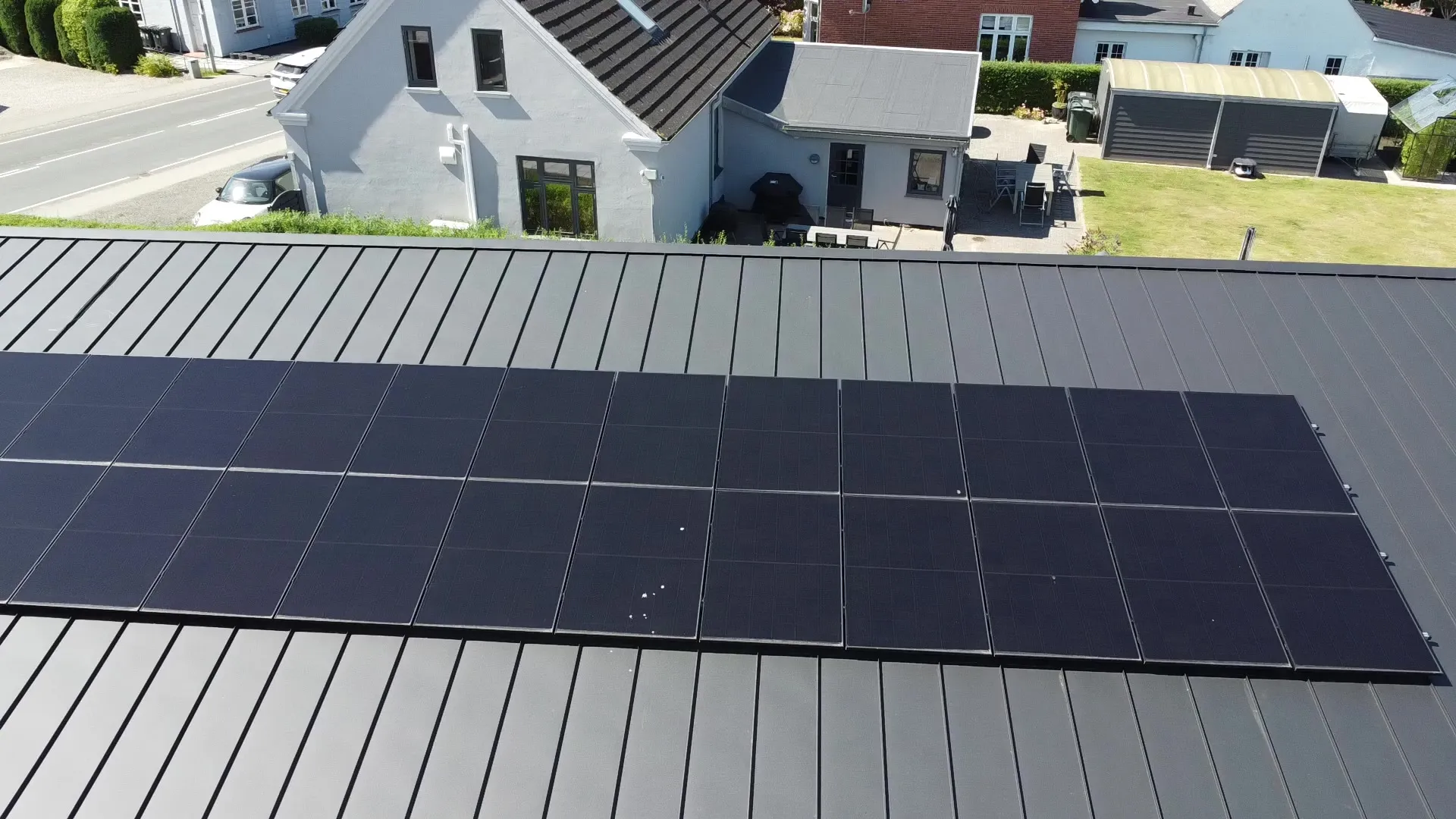 Nærbillede af solceller på klikfals-ståltaget på Assensvej 56A: panelerne sidder på falsene, ingen huller i pladen