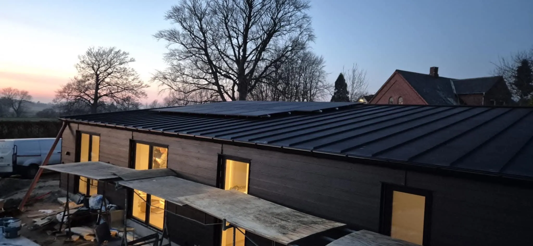 Solcelletag i morgenlys med lys i vinduerne nedenunder