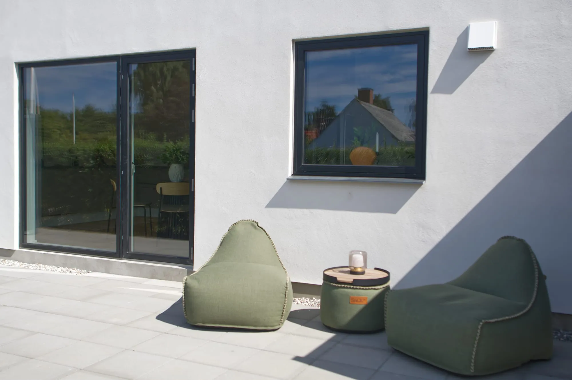 Flisebelagt terrasse på Assensvej 56A med hvid facade og sorte partier